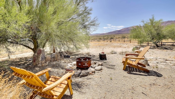 A desert campsite with two wooden Adirondack chairs, a metal fire pit, and a wooden table. - Borrego Springs Stargazing Home w/ Mtn Views (Borrego Springs)