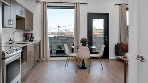 A modern kitchen with a dining area, a black door, and a view of buildings outside. - GULCH Condo with Pool, Gym, Private Patio & Garage (Nashville)