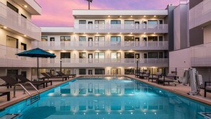 A multi-story hotel with a swimming pool, balconies, and outdoor seating. - GULCH Condo with Pool, Gym, Private Patio & Garage (Nashville)