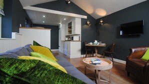 A modern living room with a sofa, coffee table, and a dining area. - Courtyard Cottages Lymington (Lymington)