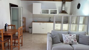 A compact living space with a dining area, kitchenette, and a sofa with floral cushions.
