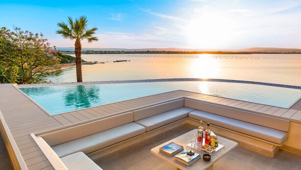 A poolside area with a built-in bench and a table with drinks and snacks.