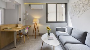 A modern living room with a grey sofa, a wooden desk, a white coffee table, and a floor lamp. - Heyden 3 · Top Floor Renv 3BDR APT / “Pedion tou (Athens)