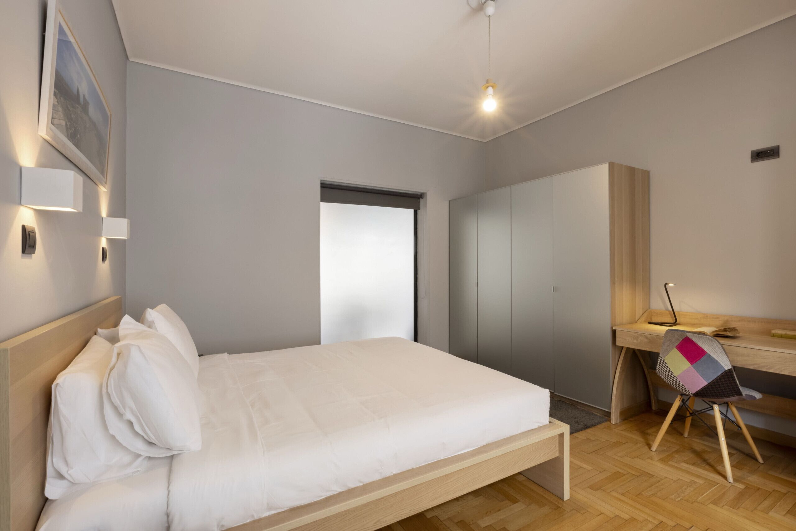A modern bedroom with a bed, bedside tables, a desk, and a chair.
