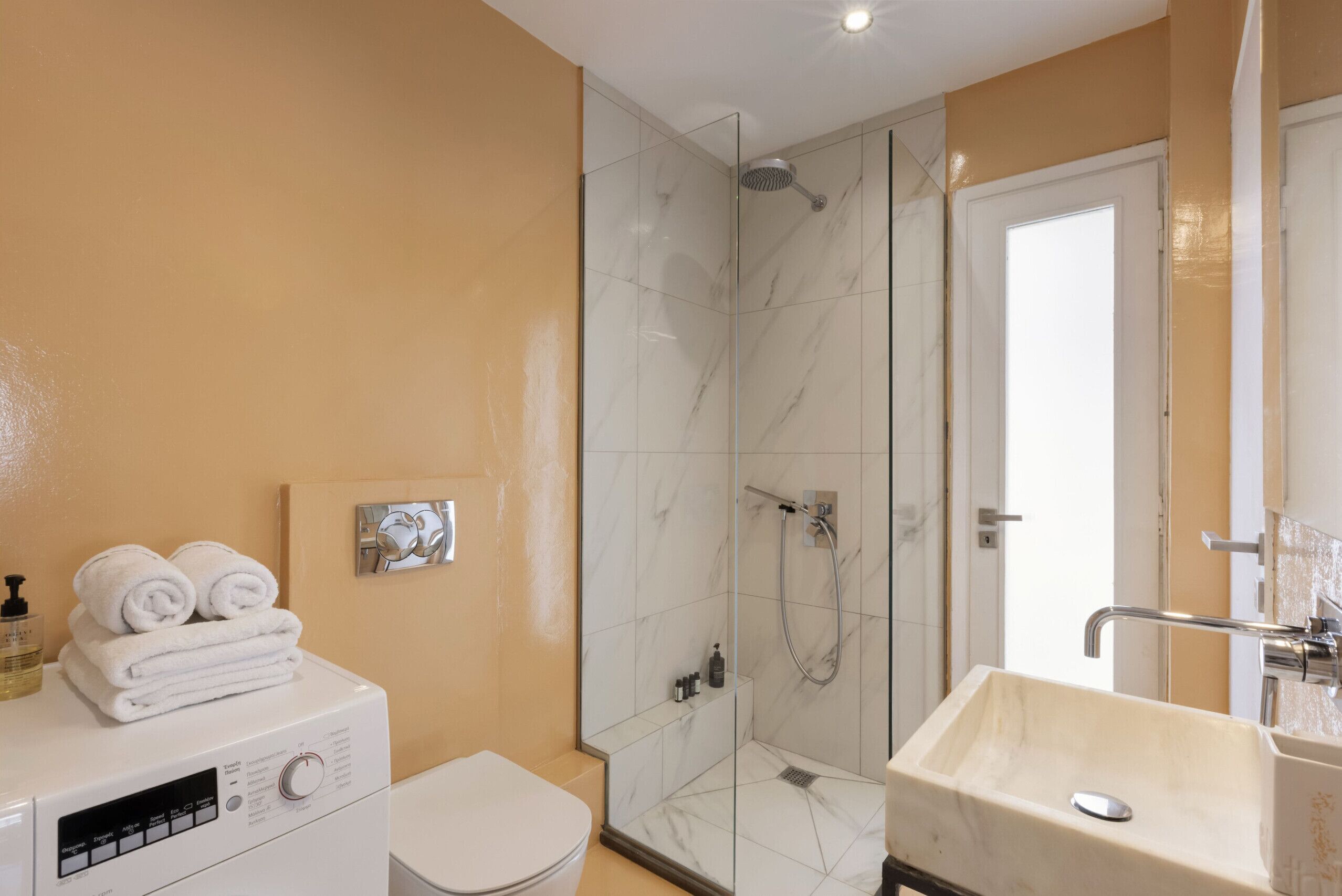 A bathroom with a glass-enclosed shower, a sink, and a toilet.