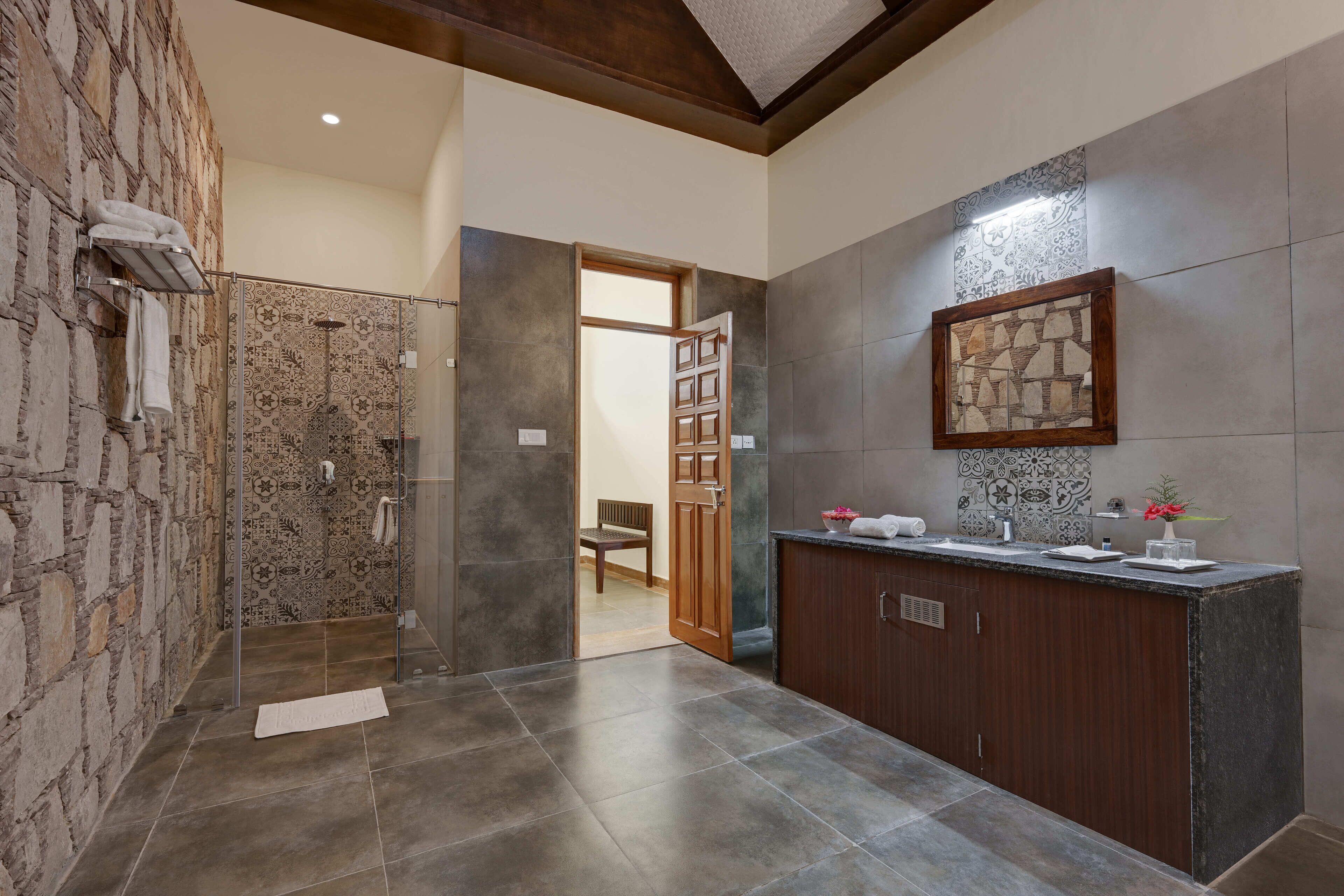 A modern bathroom with a shower, a vanity with a mirror, and a stone wall.