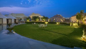 A well-maintained outdoor area with a grassy lawn, a pool, and several buildings with distinct architectural styles. - The Sawai Bagh (Sawai Madhopur)