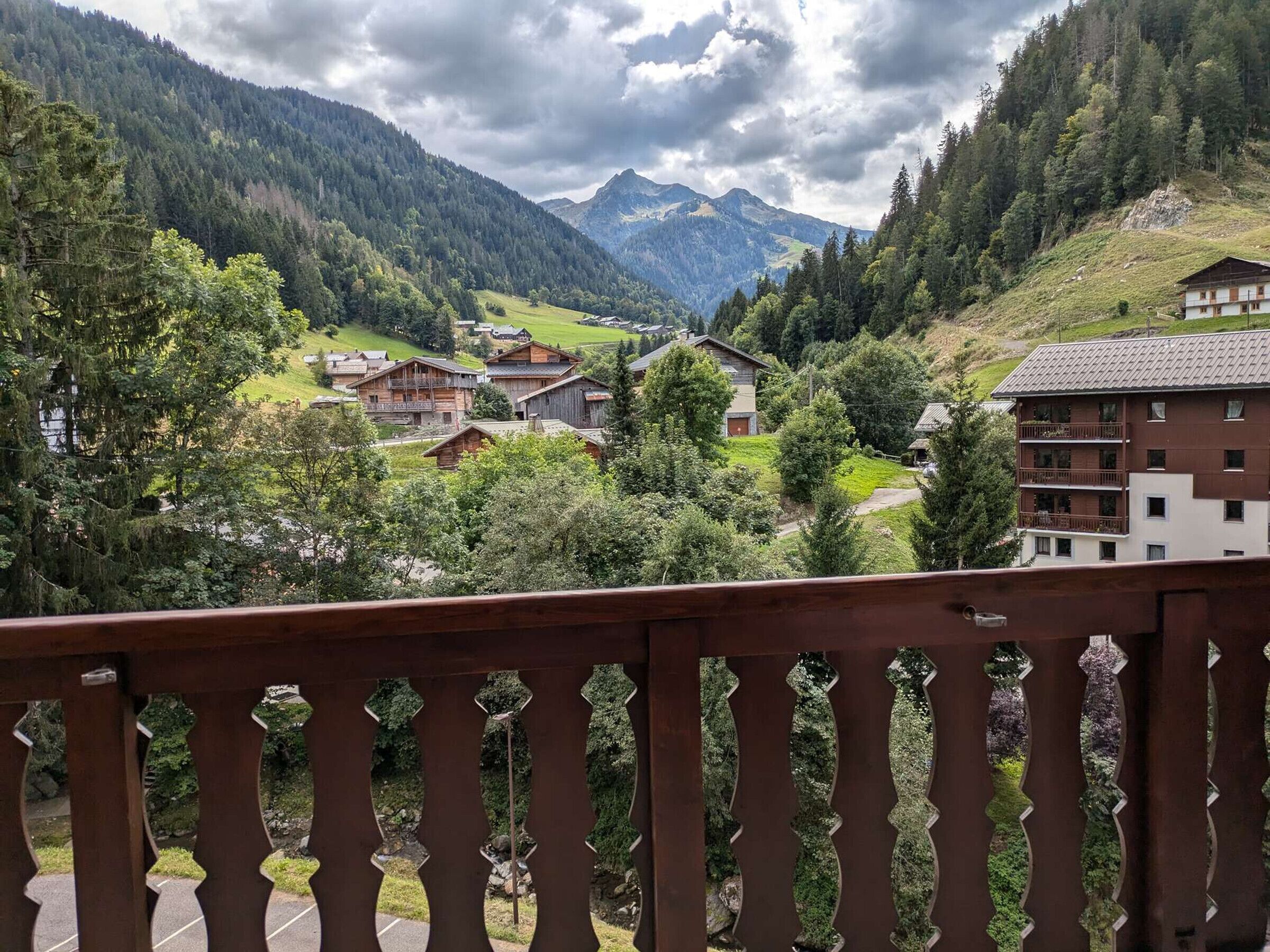 A mountainous landscape with a village, featuring traditional wooden houses and a modern building with balconies.