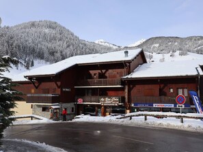 A wooden building with a restaurant sign, a ski lift, and a mountain backdrop. - Cozy Apartment for 5, South-Facing, Central Village, Near Ski Lifts, Pool, WiFi (Arêches-Beaufort)