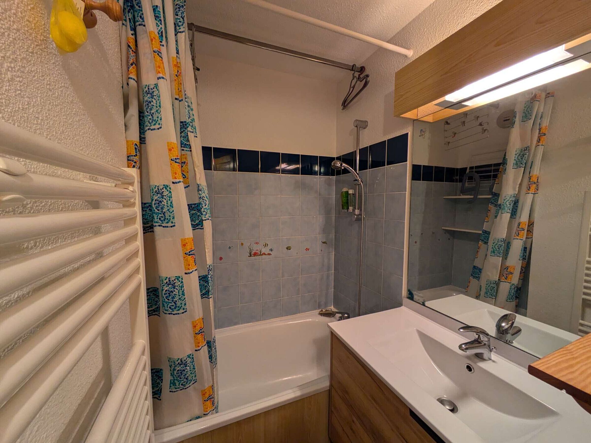 Een badkamer met een bad, douche en wastafel met spiegel.
