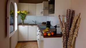 A compact kitchen with white cabinets, a built-in oven, and a fruit bowl on the counter. - El Refugio Apartments & Villa; El Teide - Honeymoon (La Matanza de Acentejo)