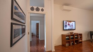 A hallway with framed pictures, a television, and a wooden bookshelf. - Comfortable tastefully furnished apartment in a strategic position (Bergamo)