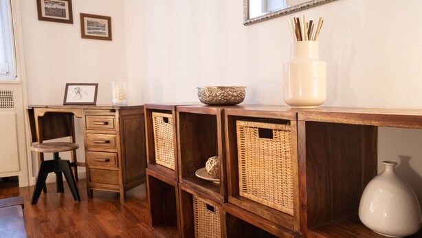 A room with a wooden desk, wicker baskets, and a white vase on a shelf. - Comfortable tastefully furnished apartment in a strategic position (Bergamo)