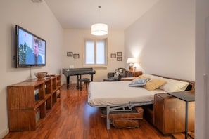 Ein Schlafzimmer mit Bett, Klavier, Fernseher und Schreibtisch.