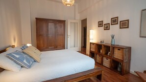 A bedroom with a wooden bed, a wooden wardrobe, and a bedside table with baskets. - Comfortable tastefully furnished apartment in a strategic position (Bergamo)