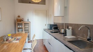 A compact kitchen with a wooden dining table, a built-in oven, a coffee maker, and a sink. - Comfortable tastefully furnished apartment in a strategic position (Bergamo)