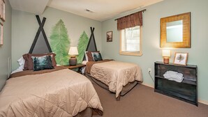 Une chambre avec deux lits, une table de chevet, une lampe, un miroir et une étagère avec des serviettes.