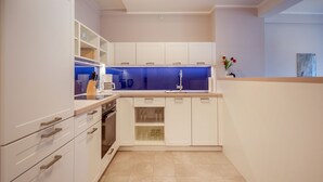 A modern kitchen with white cabinetry, a built-in oven, and a blue backsplash. - Beautiful apartment in top beach location with sea view (Ostseebad Binz)