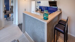 Une cuisine moderne avec un îlot central, des meubles blancs et un pare-feu bleu.