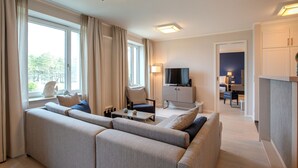 Un salon moderne doté d’un grand canapé d’angle, d’un téléviseur et d’un coin repas avec une table et des chaises.