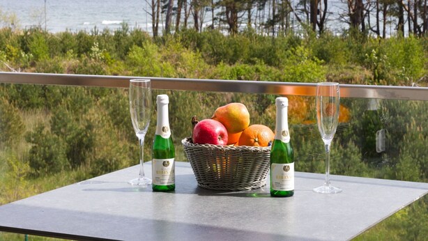 Ein Tisch mit einer Weinflasche, einem Glas und einem Obstkorb mit Blick auf das Meer.