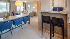 Une cuisine moderne dotée d’un îlot central, de tabourets de bar bleus et d’un coin repas avec une table et des chaises.