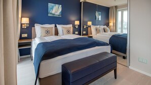 Une chambre d’hôtel moderne avec deux lits, un grand miroir et une vue sur l’extérieur.