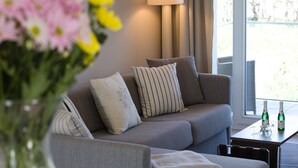 Uma sala de estar moderna com um sofá cinza, almofadas listradas e um vaso de flores.