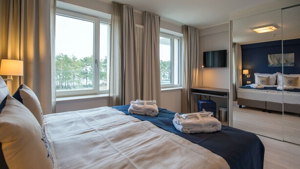Quarto de hotel com uma cama grande, uma mesa, uma cadeira e uma televisão.