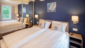 Una habitación de hotel con una cama grande, una mesita de noche, un espejo y un cuadro en la pared.