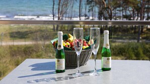 A table with two bottles of Schlosser Kylling wine, a fruit basket, and three wine glasses on a balcony overlooking the ocean. - Apartment with sea view, 2 bedrooms and balcony (Ostseebad Binz)