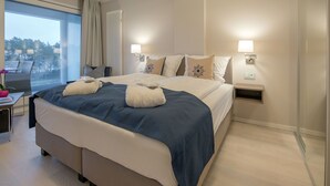 Een moderne hotelkamer met een groot bed, nachtkastjes, een raam met uitzicht en een klein bureau met stoel.