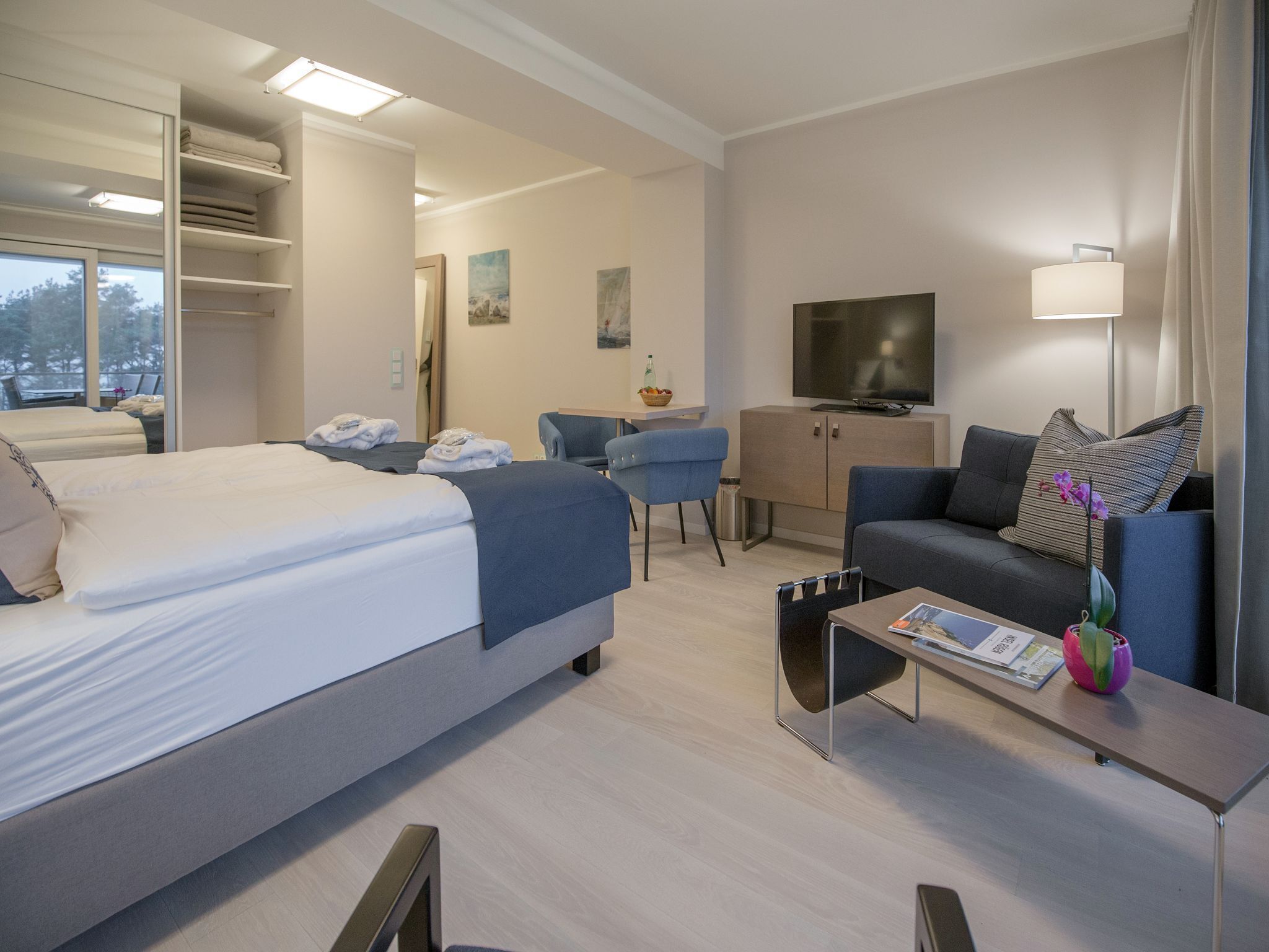 Ein modernes Hotelzimmer mit einem großen Bett, einer Couch, einem Schreibtisch und einem Fernseher.