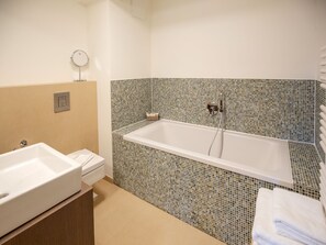 A bathroom with a white bathtub, a sink, and a toilet. - Apartment with a view of the sea, 1 bedroom, and a balcony (Ostseebad Binz)