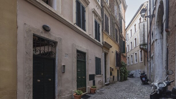 A narrow cobblestone street with buildings on either side, featuring traditional doors and windows, and a parked scooter on the right. - GuestHost - Nice and cozy apartment of 35 sqm, ideal for 2 people, located on the first floor of a renovated period building (not equipped with lift). The flat is located in very central position, just 200 meters from Piazza Navona and a few steps from o (Roma)