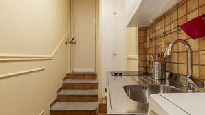 A kitchen with a stainless steel sink, a red pot rack, and a staircase leading to a door. - GuestHost - Nice and cozy apartment of 35 sqm, ideal for 2 people, located on the first floor of a renovated period building (not equipped with lift). The flat is located in very central position, just 200 meters from Piazza Navona and a few steps from o (Roma)