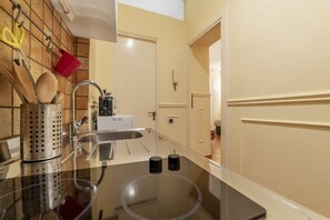 A kitchen with a stainless steel sink, a coffee maker, and utensils hanging on the wall.