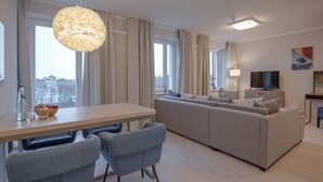 A modern living room with a sofa, chairs, a dining table, and a TV. - Sky suite with unobstructed sea view, roof terrace and balcony (Ostseebad Binz)