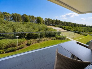 Un balcon donnant sur un jardin aménagé et une route.