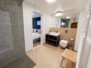 Une salle de bain moderne avec une douche à parois de verre, un lavabo avec un miroir et un petit banc en bois.
