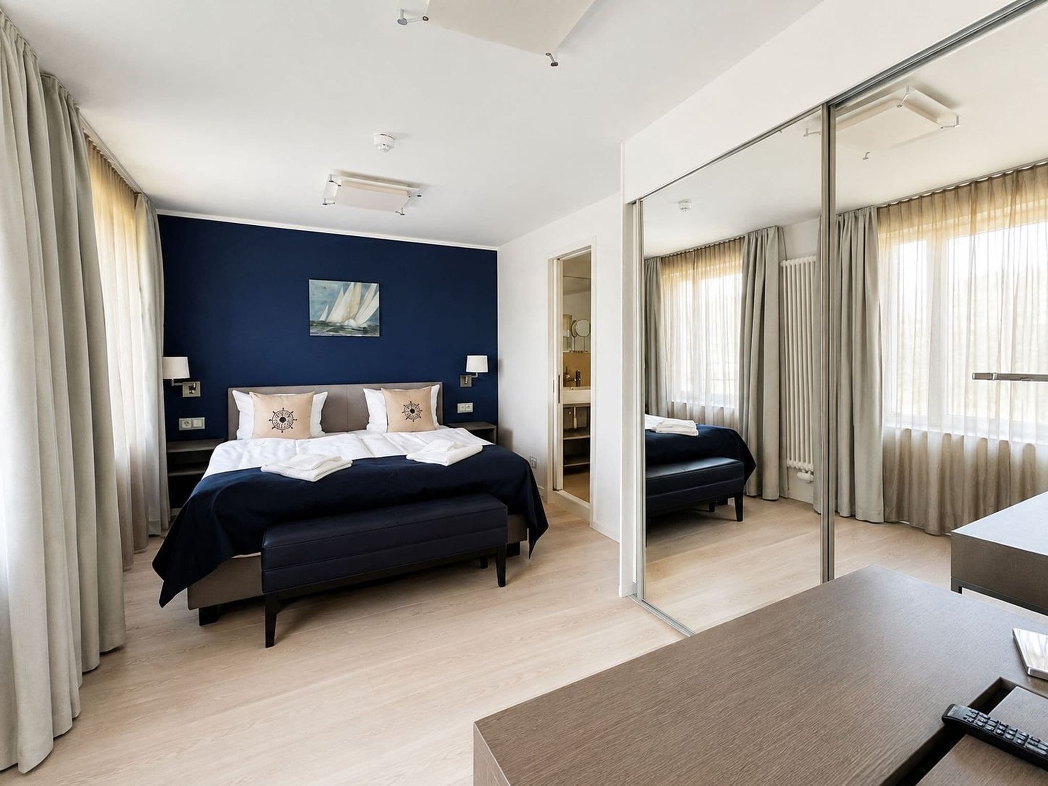 Una habitación de hotel moderna con una cama grande, un escritorio y un espejo.