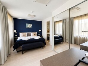 Une chambre d’hôtel moderne avec un grand lit, un bureau et un miroir.