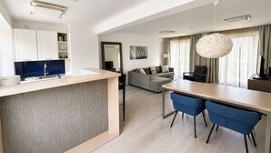 A modern kitchen with a dining area, a sofa, and a large window with curtains. - Apartment with sea view, 1 bedroom and balcony (Ostseebad Binz)