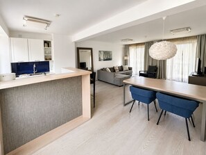 Eine moderne Küche mit Essbereich, einer Couch und einem großen Fenster mit Vorhängen.