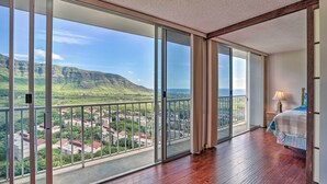 Een ruim balkon met uitzicht op een bergachtig landschap en een woongebied.