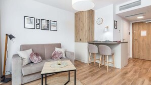 A modern living room with a sofa, a coffee table, and a kitchen area with a bar. - Seaside Studio with Balcony | 50 m to the Beach | Parking (Mielno)