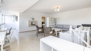 En rummelig opholdsstue med sofa, stole, spisebord og bogreol.
