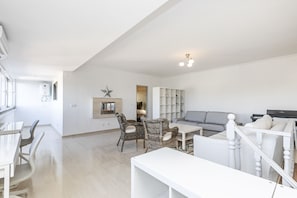 Un amplio salón con sofá, sillas, una mesa de comedor y una estantería.