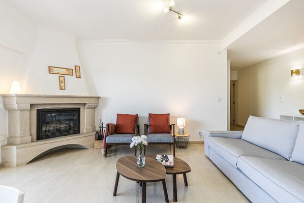 Ein Wohnzimmer mit Kamin, zwei Sofas, einem Couchtisch und einem Beistelltisch mit Lampe.