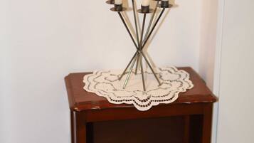 A small wooden side table with a lace doily and a candle holder with white candles.